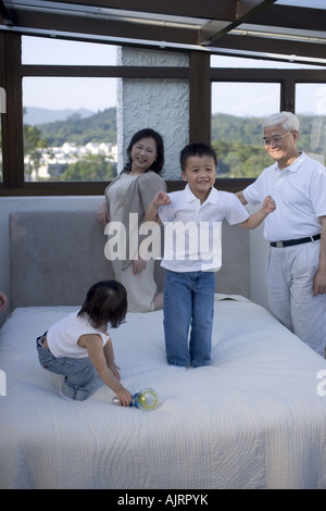 Les grands-parents à leur petit-fils et sa petite-fille à jouer sur le lit Banque D'Images