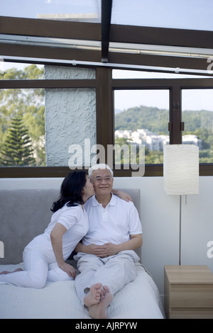 Senior woman kissing a senior man sur le lit Banque D'Images