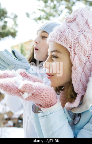 Deux jeunes amis holding up poignées de neige, side view Banque D'Images