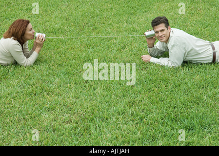 Mature couple allongé sur le sol, à se parler par tin can phone Banque D'Images