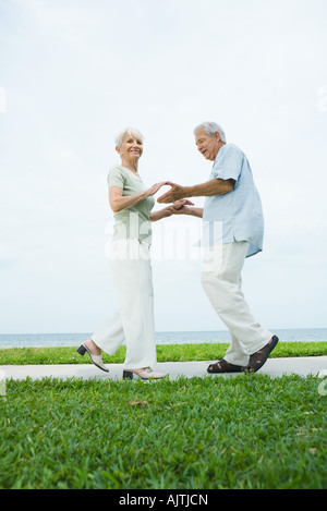 Senior couple dancing on sidewalk overlooking ocean, pleine longueur Banque D'Images