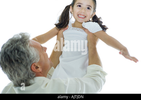 Homme mûr, levant petite fille dans l'air Banque D'Images