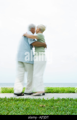 Senior couple dancing on sidewalk overlooking ocean, pleine longueur, blurred motion Banque D'Images