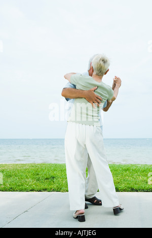 Senior couple dancing on sidewalk overlooking ocean, pleine longueur Banque D'Images