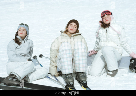 Trois skieurs teen girl sitting in snow, les yeux clos, la tête en arrière Banque D'Images