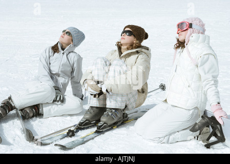 Trois skieurs teen girl sitting in snow, portant des lunettes de soleil, la tête en arrière Banque D'Images