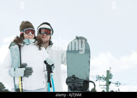 Jeune couple habillé en vêtements de ski, snowboard, man holding woman holding bâtons de ski Banque D'Images