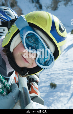 Jeune fille portant des lunettes de ski et casque, smiling at camera, portrait Banque D'Images