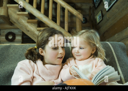 Preteen girl reading book avec tout-petit Banque D'Images