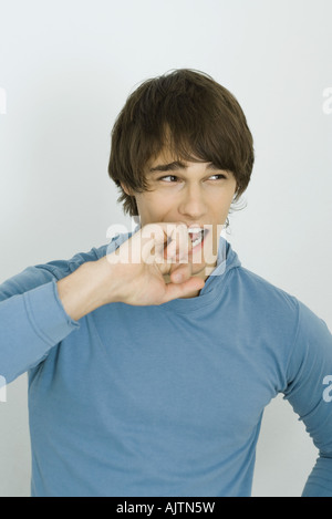 Young man biting knuckles, looking away, portrait Banque D'Images