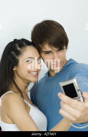 Young couple taking self portrait with digital camera, woman smiling at camera Banque D'Images