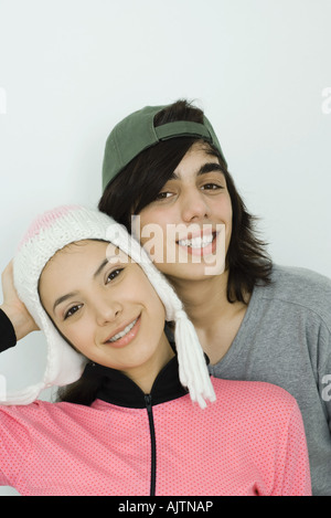 Young couple smiling at camera ensemble, à la fois porter un chapeau, joue contre joue, portrait Banque D'Images