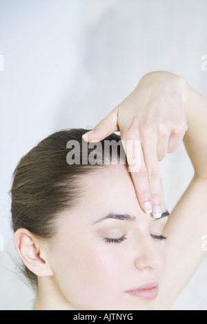 Jeune femme de toucher le front, les yeux fermés, cropped view Banque D'Images