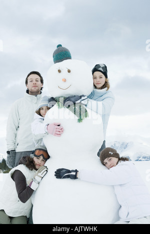 Jeunes amis regroupés autour de snowman, posing, portrait Banque D'Images