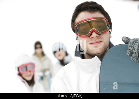 Jeune homme debout avec des neiges, les amis en arrière-plan, Portrait Banque D'Images