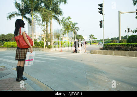 Jeune femme en attente de cross street Banque D'Images