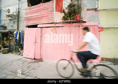 La Chine, la province de Guangdong, Guangzhou, man riding bicycle par street Banque D'Images