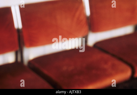 Soft focus détail de trois chaises en velours rouge profond dans une rangée alignés contre un mur blanc Banque D'Images