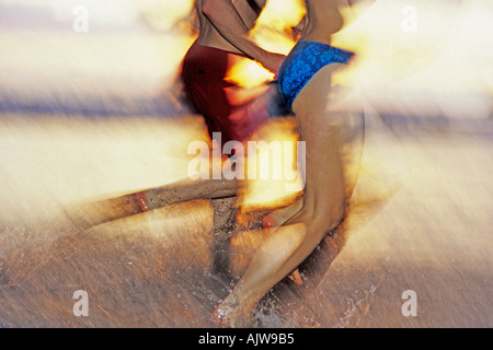 COSTA RICA COUPLE RUNNING ON BEACH AT SUNSET Banque D'Images