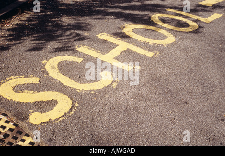 Sign painted on road et l'École d'avertissement avec un couvercle de trou d'homme et l'ombre d'un arbre Banque D'Images