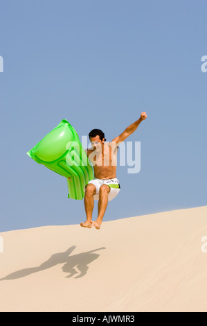 Jeune homme sauter d'une dune de sable Banque D'Images