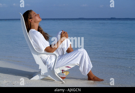 Maldives.Jeune femme assise sur chaise de plage. Banque D'Images