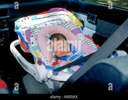 Un bébé de quatre mois en un siège de voiture qui s'est tenue en place par les ceintures de sécurité Banque D'Images