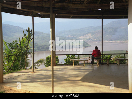 Homme assis sous la pagode en bois de la vallée impressionnante à regarder avec étonnement Mékong Huay Xai Laos Asie du sud-est Banque D'Images