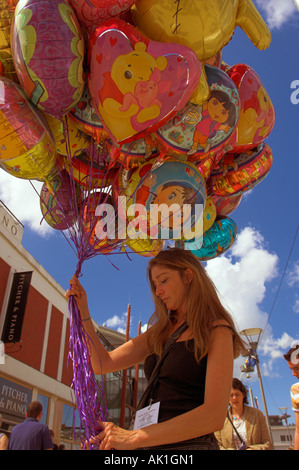 Vendeur de rue femme de caractère coloré ballons à l'hélium avec des visages souriants contre le ciel bleu Banque D'Images