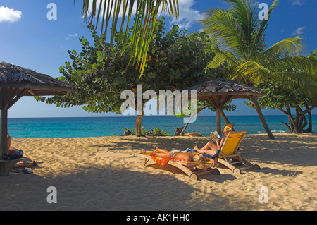 Les touristes sur une plage de sable sous les palmiers avec vue sur la mer et le ciel bleu Banque D'Images