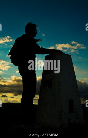 Walker à l'trig point au sommet de mont du Pain de Sucre Black Mountains Le Parc National des Brecon Beacons au coucher du soleil Banque D'Images