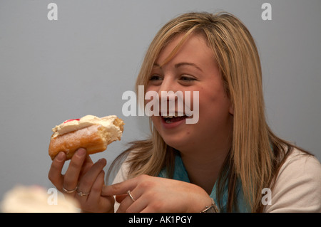 Irlandais blond teenage student laughing en mangeant une pâtisserie crème fraîche avec des amis à l'intérieur dans un café Banque D'Images