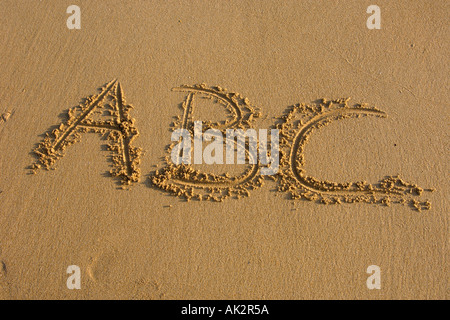 La main d'écrire des lettres de l'alphabet sur le sable Banque D'Images