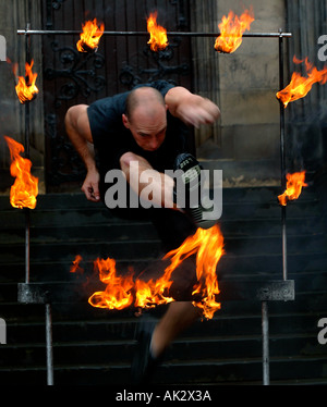 Artiste de la rue de sexe masculin en sautant à travers le cadre en métal entouré de flammes Banque D'Images