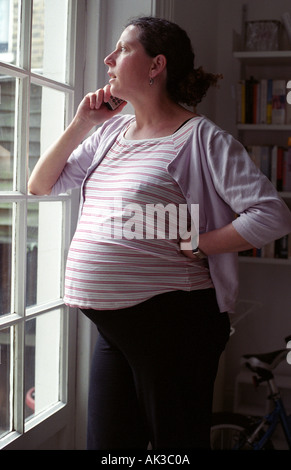 Une femme enceinte sur le téléphone à la maison, Londres, Royaume-Uni. Banque D'Images