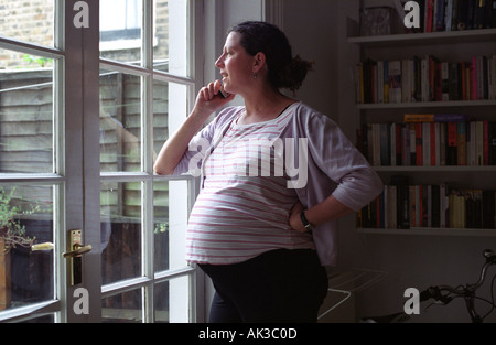 Une femme enceinte sur le téléphone à la maison, Londres, Royaume-Uni. Banque D'Images