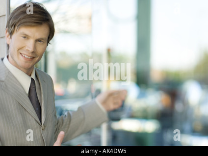 Young businessman smiling at camera and gesturing Banque D'Images