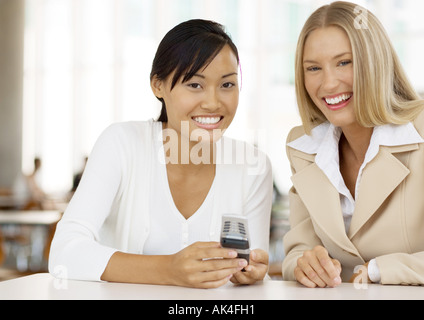 Deux employés de bureau, holding cell phone, smiling Banque D'Images
