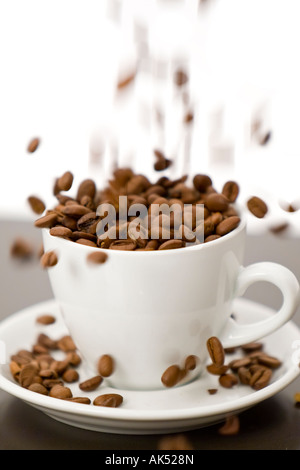 Motion blurred portrait de grains de café est versé dans une tasse et soucoupe blanc Banque D'Images