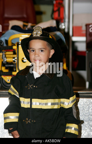 Young African American boy vêtu d'un uniforme de pompier en face d'un ambulace Banque D'Images