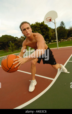 Un homme jouant un sur un baskeball dans un parc Banque D'Images