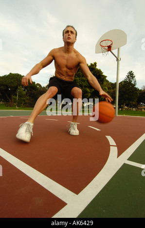 Un homme jouant un sur un baskeball dans un parc Banque D'Images