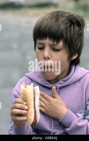 Onze ans, fille, eating a hot dog Banque D'Images