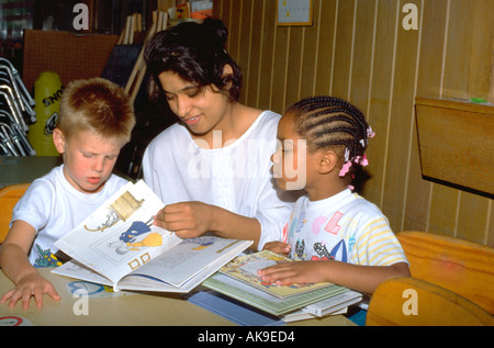 Fille de l'Est de l'Inde à l'âge de 19 livres de lecture avec deux enfants de 5 ans. St Paul Minnesota USA Banque D'Images