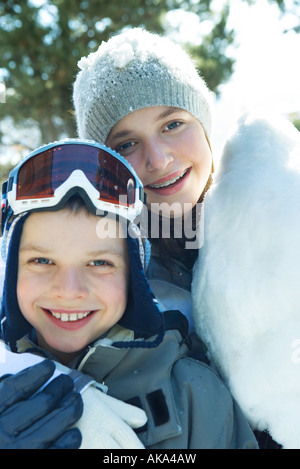 Brother and sister smiling at camera, joue contre joue, vêtu de vêtements d'hiver, portrait Banque D'Images
