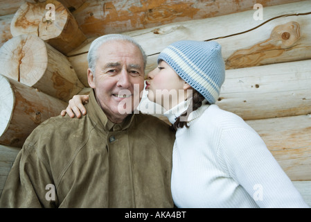 Senior man smiling at camera, petite-fille s'embrasser sa joue, portrait Banque D'Images