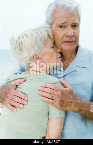 Couple, man holding woman étroitement contre lui, looking at camera Banque D'Images