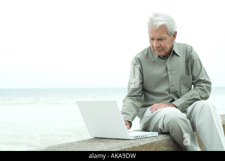 Senior man sitting outdoors, looking down Banque D'Images