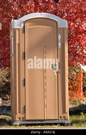 Il s'agit d'une photo d'un porta potty assis en face d'un arbre d'érable rouge. Banque D'Images