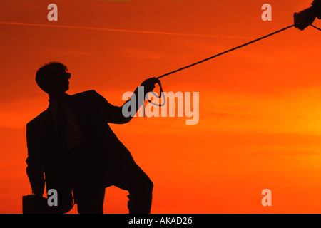 Businessman silhouette au coucher du soleil avec une corde et un porte-documents Banque D'Images